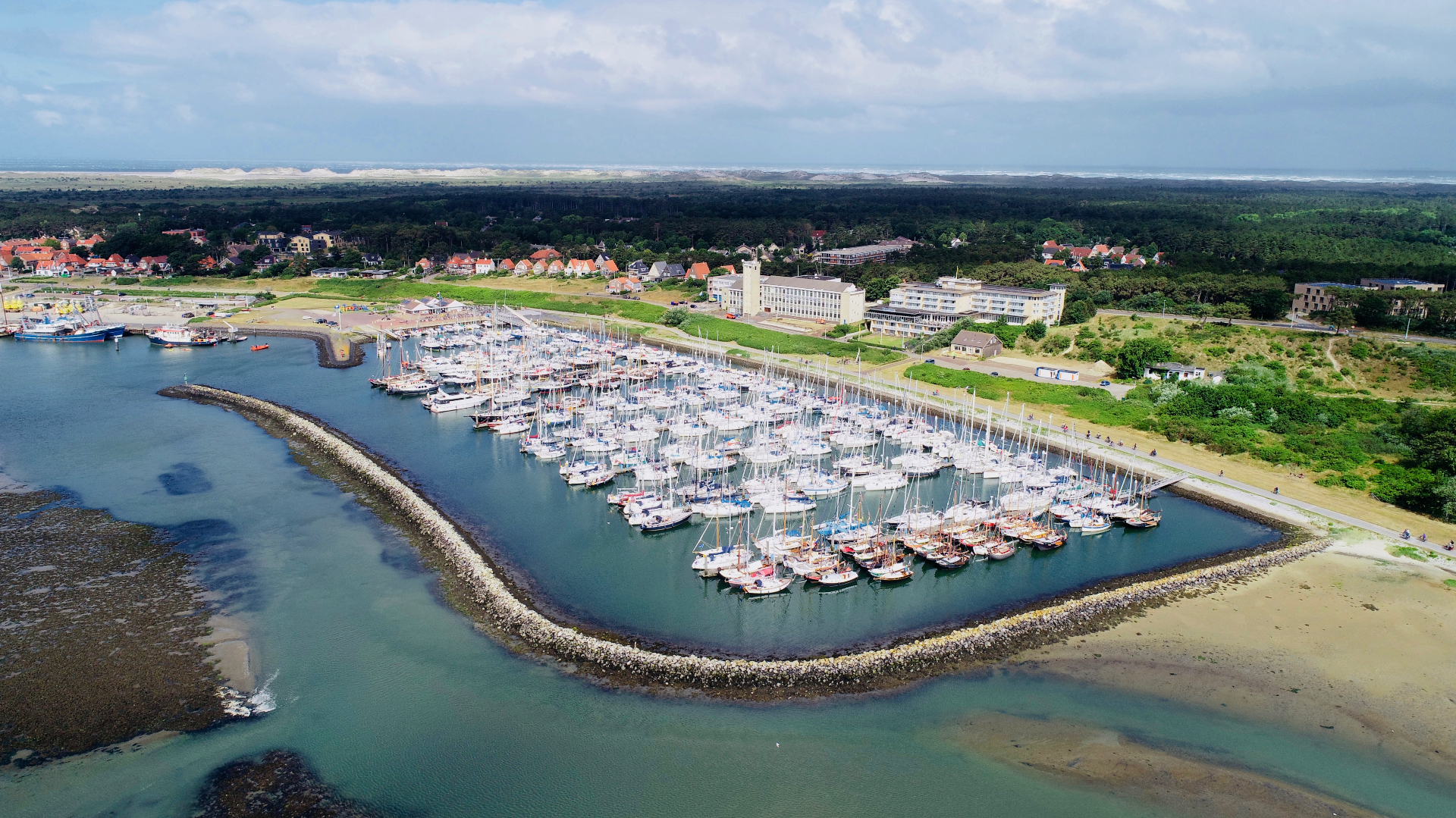Luchtfoto van de jachthaven van West-Terschelling met uitzicht op de duinen en Noordzee