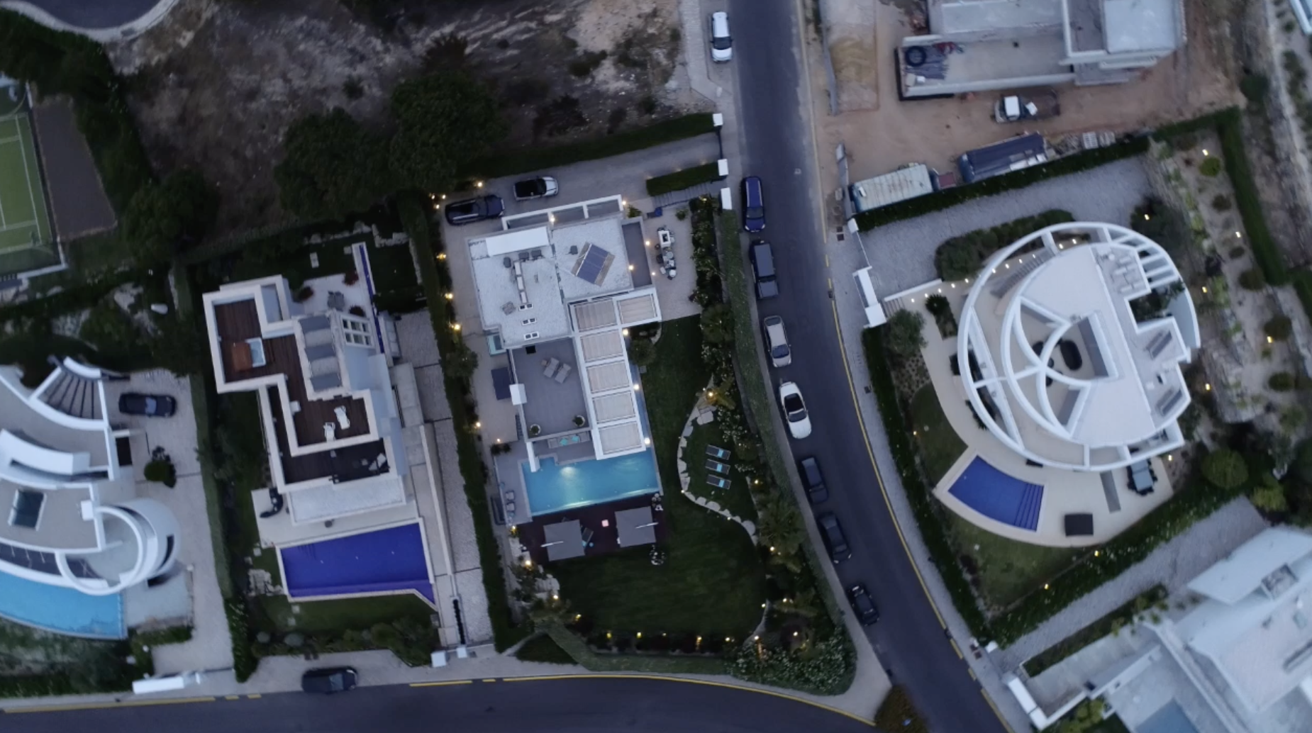 Top-down luchtfoto van luxe villa's met zwembaden in de schemering