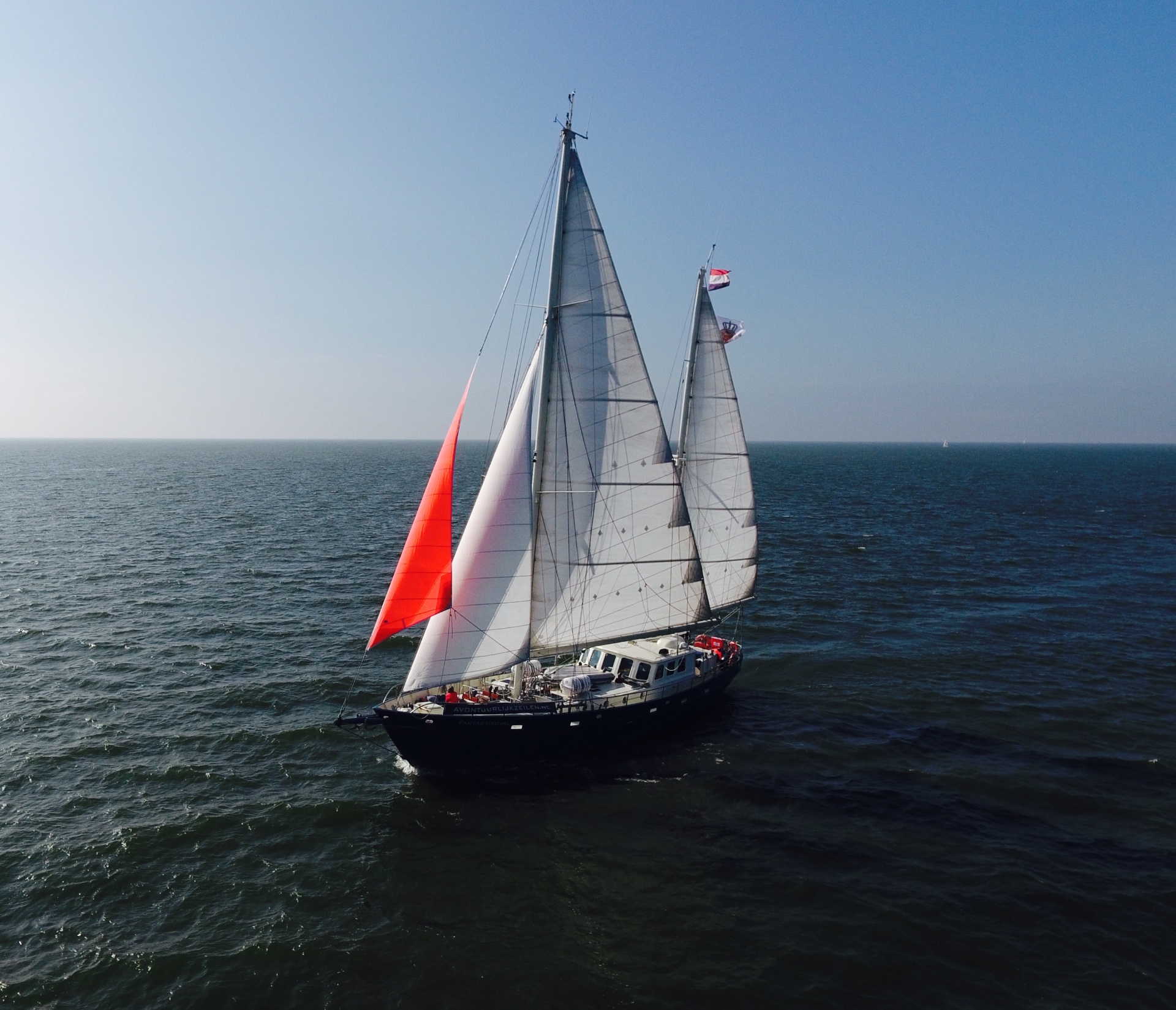 Zeilschip Fantastiko met rode fok onder volle zeilen op het IJsselmeer, vanuit de lucht