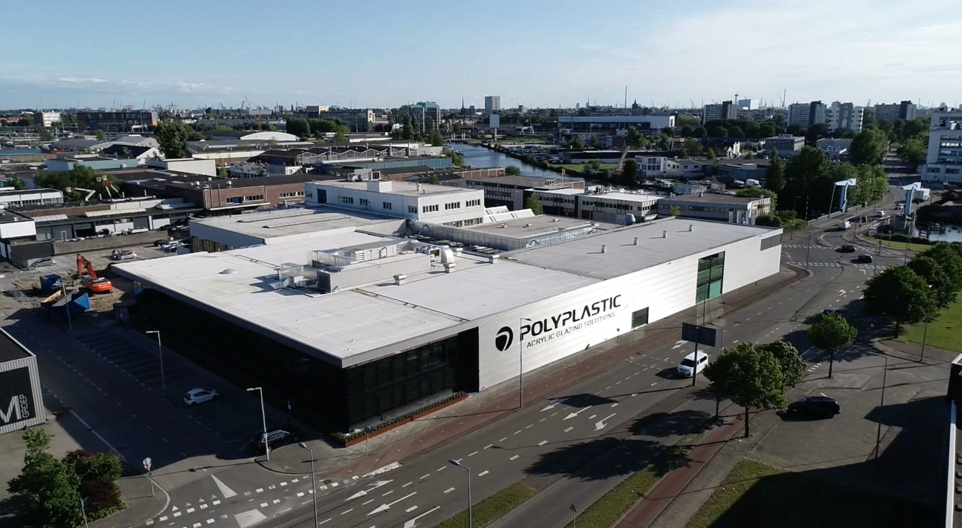 Luchtfoto van het Polyplastic bedrijfspand in Rotterdam met haven op de achtergrond
